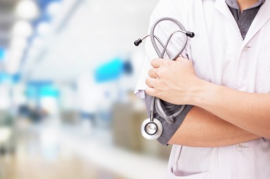 Doctor with a stethoscope in the hands and hospital background.